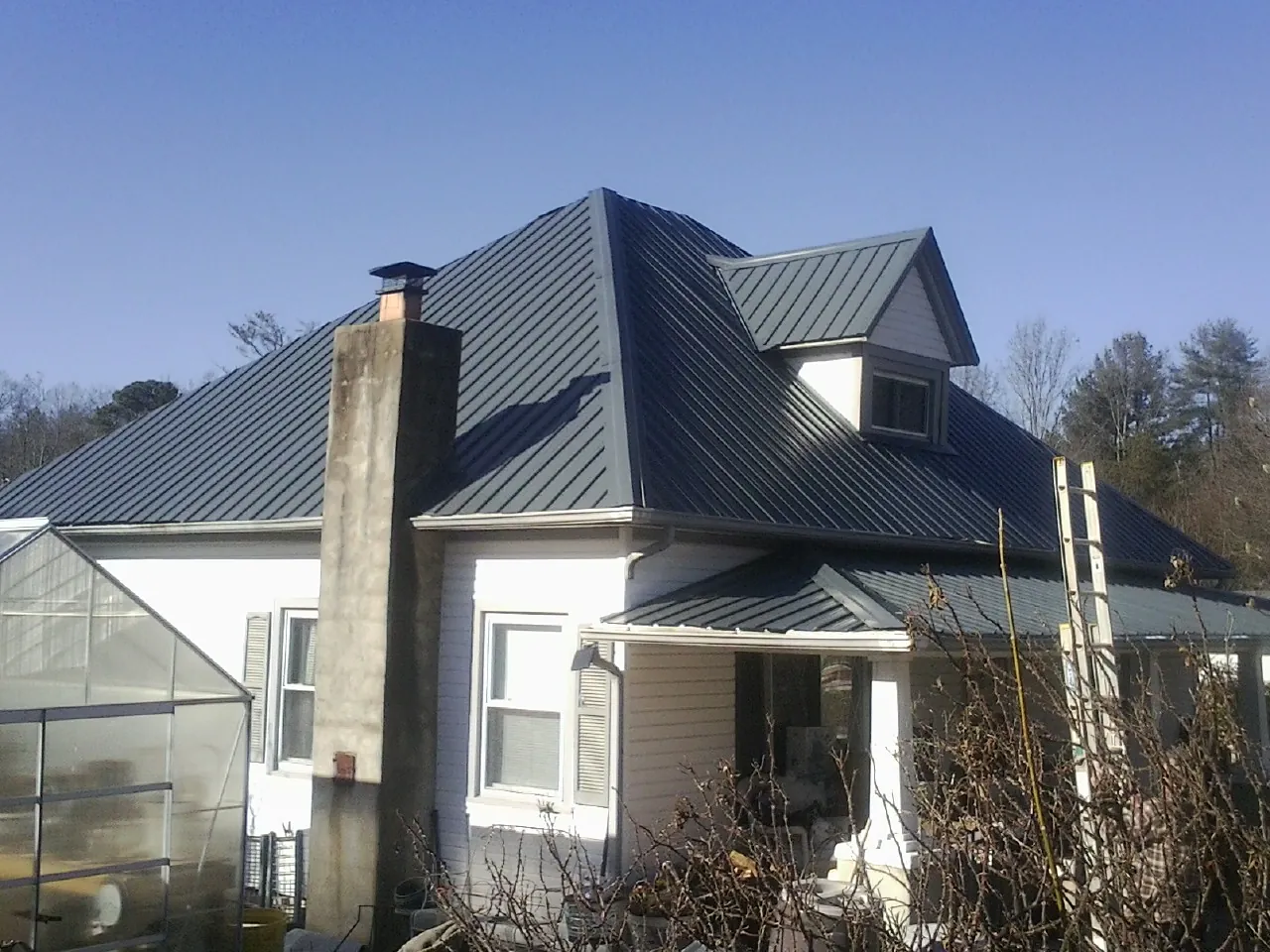 Dark blue standing seam metal roof on a white farmhouse with dormer — Slate & Tile Roof Repair by Roofing Brothers in Ranchita