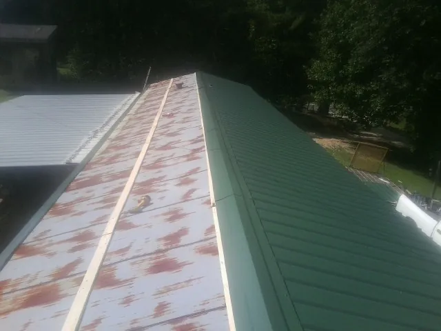 Old rusted panels beside newly installed green metal roofing — Wind Damage Roof Repair by Roofing Brothers in Ranchita