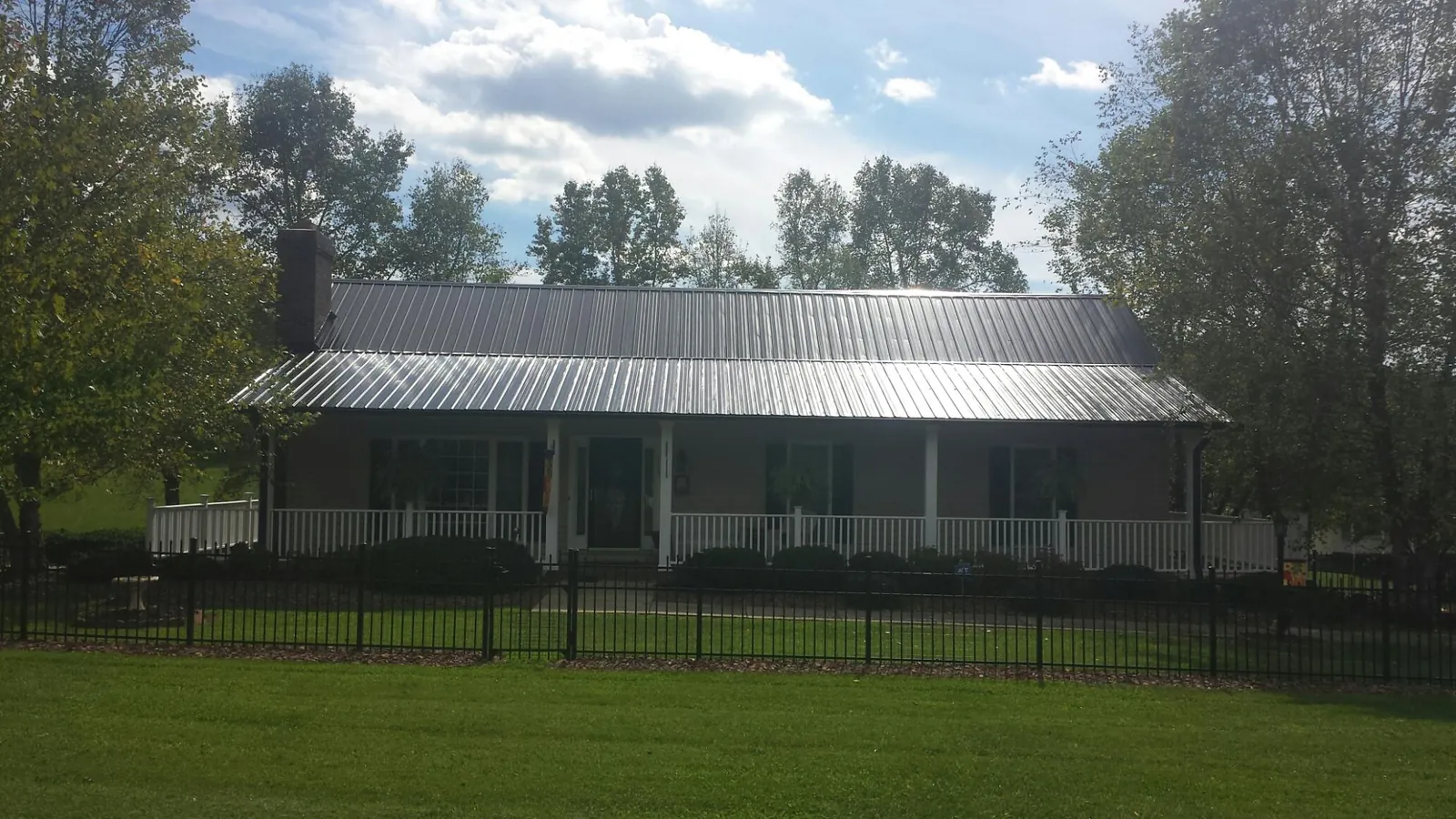 Gray metal roof on a brick ranch with a full width front porch — Gutter Guard Installation work by our crew in Ranchita