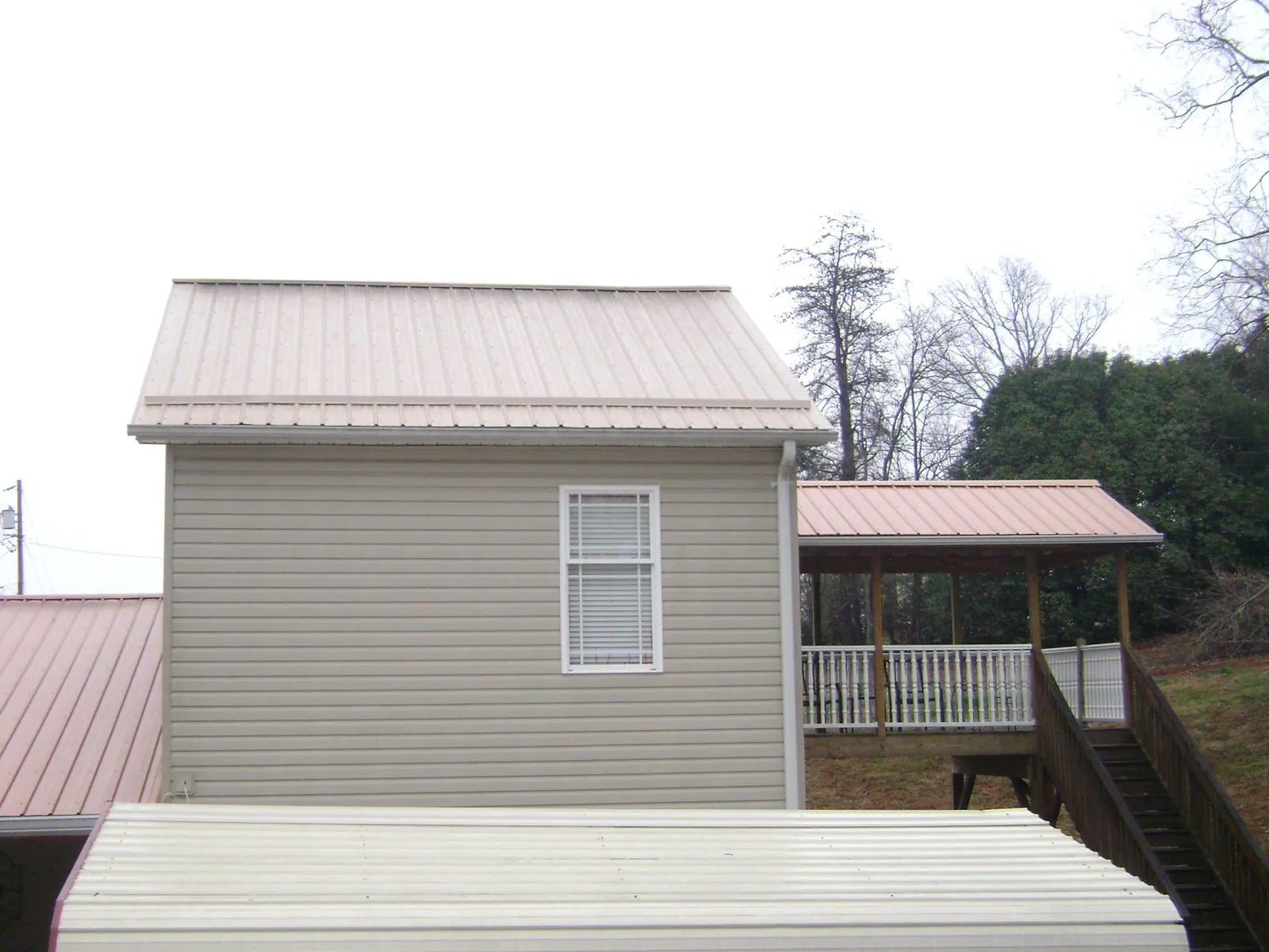 Tan metal roofs on a two story addition and attached porch, from a Roof Replacement job in Ranchita