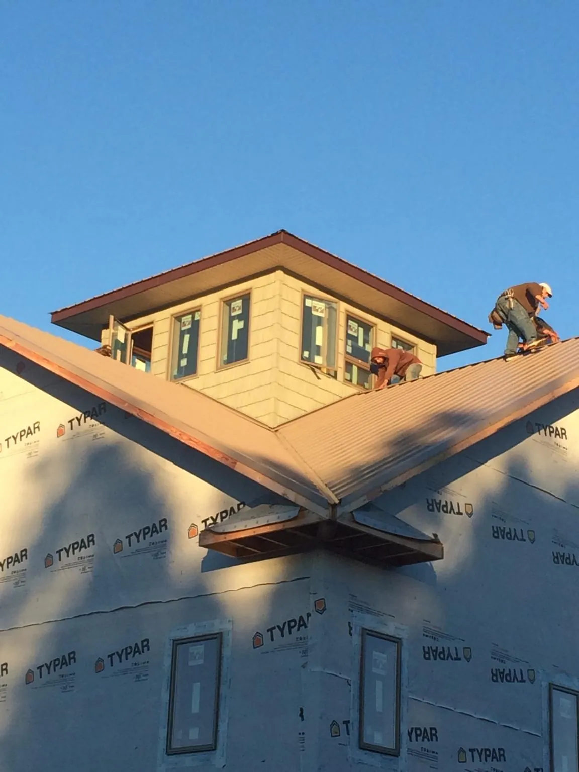 Roofers working around a rooftop cupola on a new metal roof at sunset — Roof Waterproofing in Ranchita by Roofing Brothers